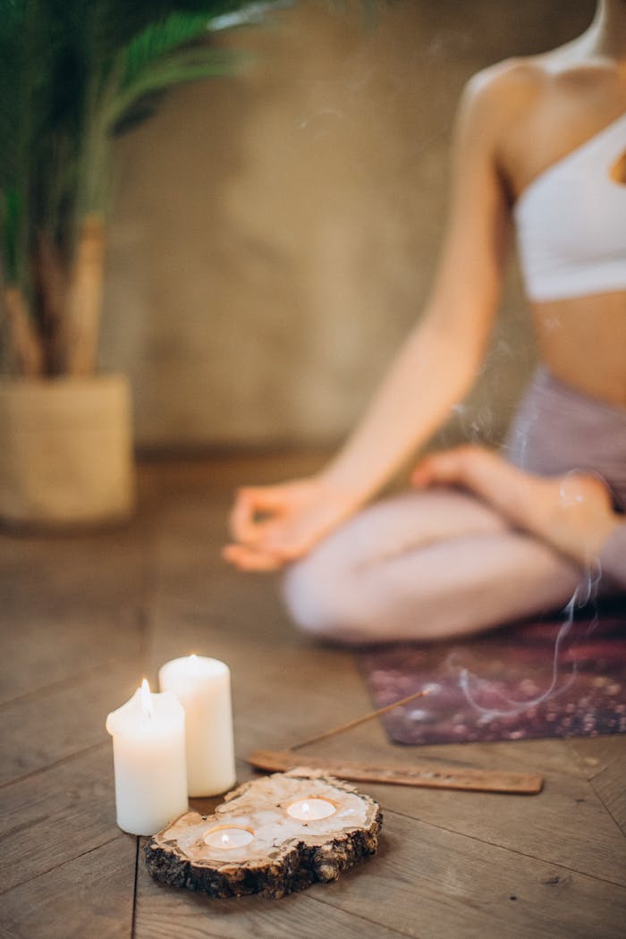 Woman practicing meditation in lotus pose with candles and incense, focusing on wellness and relaxation.